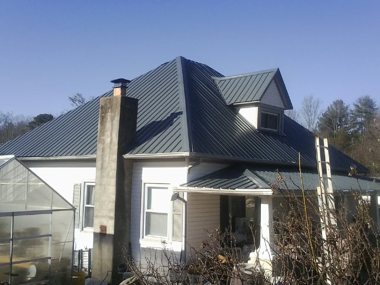 Dark blue standing seam metal roof on a white farmhouse with dormer — Slate & Tile Roof Repair by Roofing Brothers in Lyndhurst