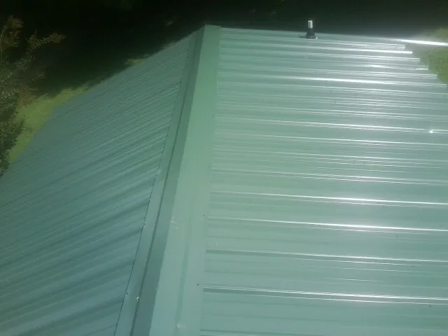 New green metal panels meeting at the ridge of a roof — Flat Roof Repair work by our crew in Lyndhurst